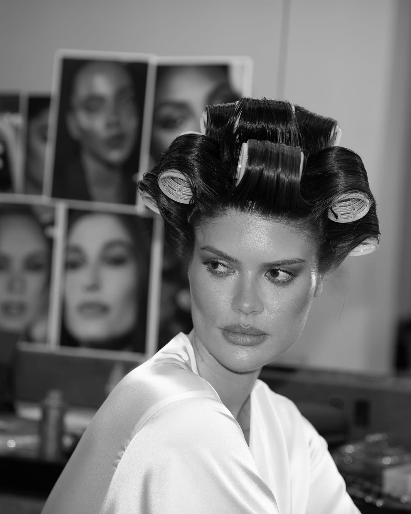 Noiva de robe de seda com bobos no cabelo, camarim em preto e branco